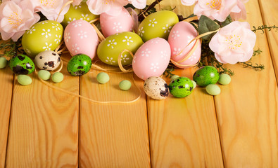 Obraz na płótnie Canvas Various Easter eggs, grass, flowers, candy, ribbon on light wood.