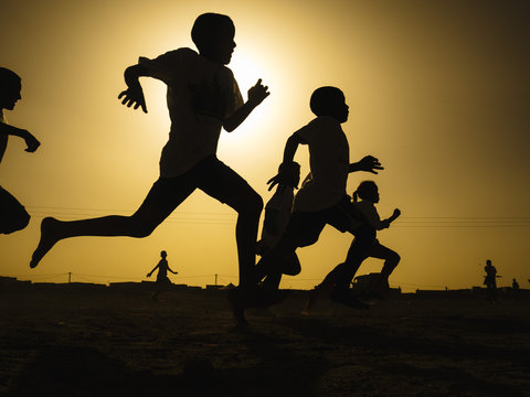 Silhouette of children running in field