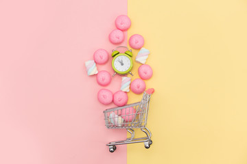 photo of marshmallows and alarm clock near shopping cart on the wonderful background in pop art style