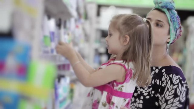 Young woman with daughter buying body care products in supermarket