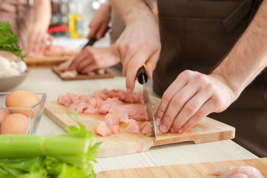 Man cutting chicken fillet at cooking classes