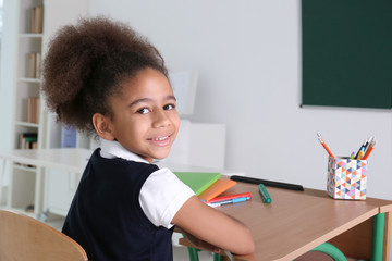 Portrait of cute African-American girl in classroom