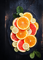Variety  sliced citrus fruit orange, grapefruit, lemon on  black  wooden board. Top view.