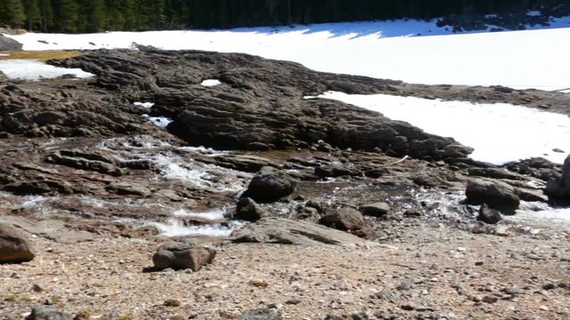 spring stream flows through  stone to  frozen lake