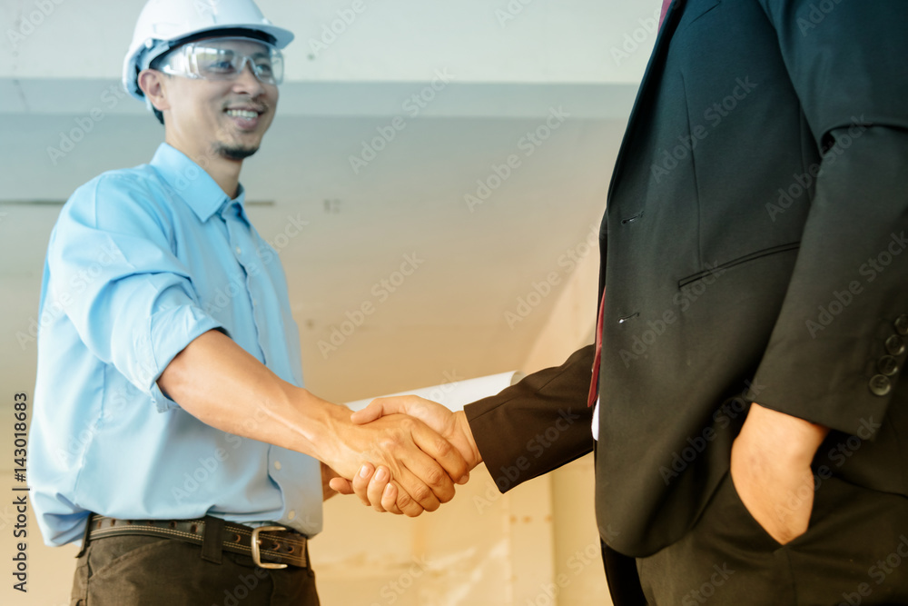 Wall mural confidence businessman shaking hands to seal a deal with engineer in building, business success conc