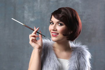 Young woman with cigarette holder on color background