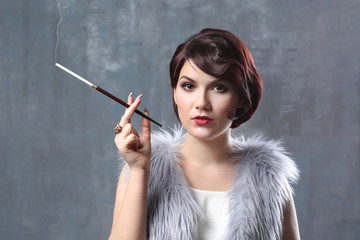 Obraz premium Young woman smoking with cigarette holder on color background
