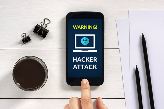 Hacker attack concept on smart phone screen with office objects on white wooden table. All screen content is designed by me. Flat lay