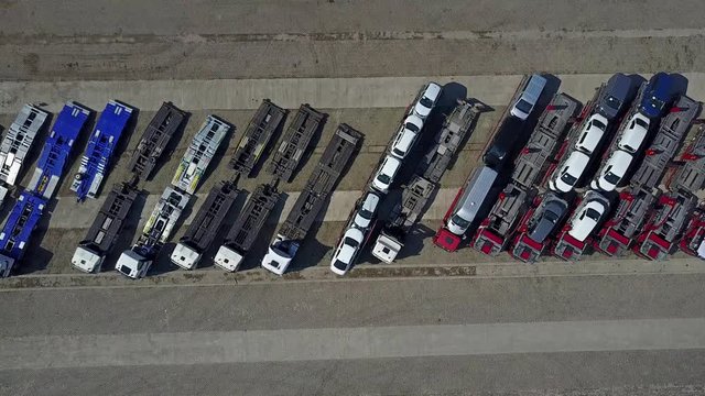 Aerial shot of parked car transporter trucks and trailers, top view. 4K video