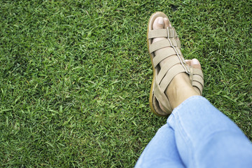 woman's feet in cream sandals on grass