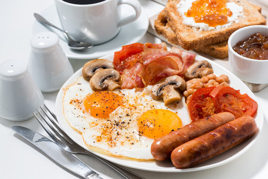English breakfast of scrambled eggs with bacon, sausages and vegetables