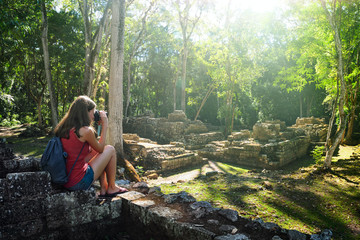 Woman traveller photographing ancient Mayan ruins.