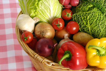 Various kind of vegetables in basket over rustic red tablecloth 