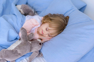 child, little girl sleeping in bed with toy rabbit