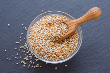 puffed amaranth in a wooden scoop and a bowl on the black background, selective focus