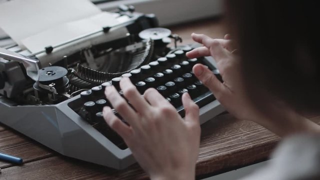Writer typing with retro writing machine. View from over shoulder.