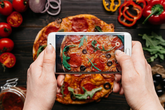 Photographing food. Hands taking picture of delisious pizza with smartphone