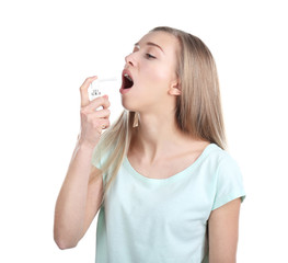 Sick young woman using throat spray on white background