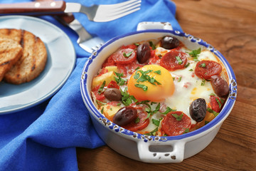 Delicious Spanish baked egg in bowl on kitchen table