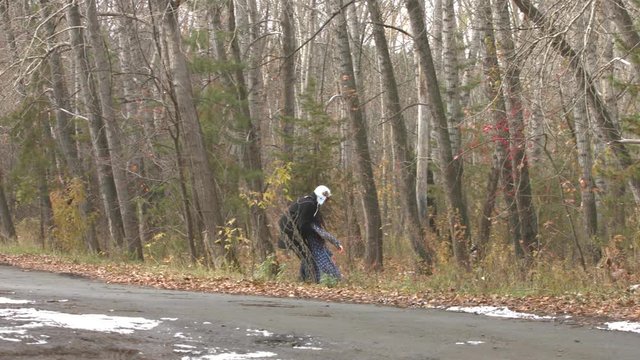 The man pulled a girl out of the woods onto the road.

A man in a black coat is dragging a young girl from the autumn forest with no signs of life.