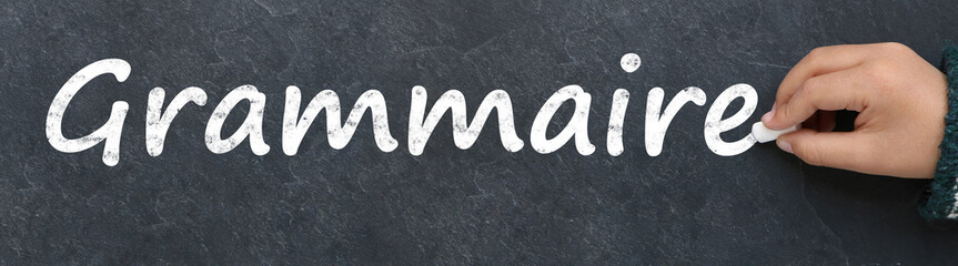 Main d'enfant écrivant grammaire à la craie sur une ardoise