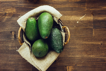 Avocado fruits in basket on wooden rustic background.