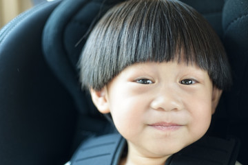 Obraz premium Portrait happy toddler boy sitting in the car seat : Soft focus