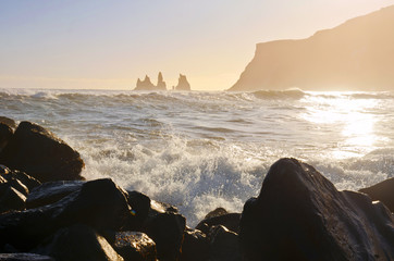 Iceland Reynisdrangar cliffs on Black sand beach in Vik with waves of the sea and gols sunset light