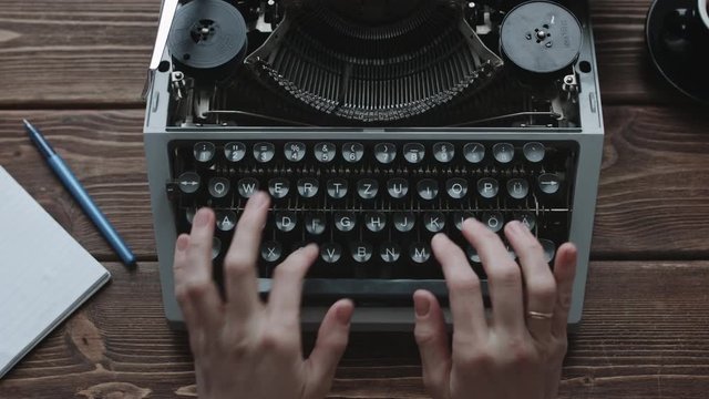 Writer typing with retro writing machine. View from above.