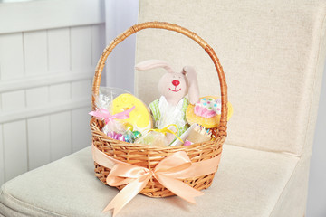 Easter basket with sweets and presents on beige chair