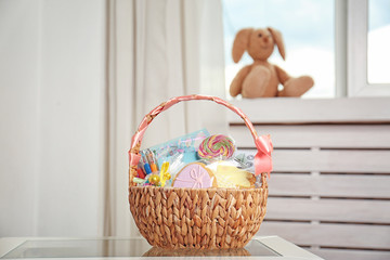 Easter basket with sweets and stationery on light background