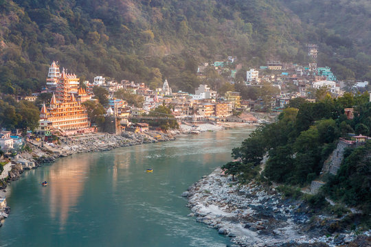 View of River Ganga and Lakshman Jhula bridge at sunset with a colorful jungles on a background and colorful houses. Rishikesh. India.
