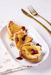 Fresh homemade crunchy popovers on a white plate on a grey concrete background. Selective focus 