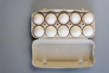 Cardboard egg rack with eggs on gray background. Top view.  Rural still life, natural organic healthy food.