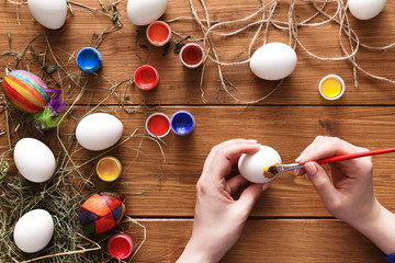 Painting colorful easter eggs, top view on wood