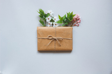 Cute gift box wrapped with craft paper and flowers top view
