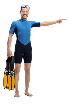 Man in a wetsuit with snorkeling equipment pointing right