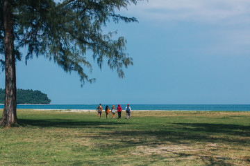 People walking to sea. Back view of people at distance walking to beach with sea on background.