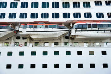 Naklejka premium orange life boat docked to a large cruise.