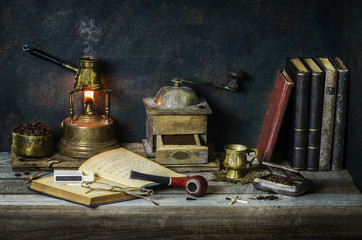 Obraz na płótnie Canvas Classic still life with hot Turkish coffee placed on alcohol burner,old coffee grinder,vintage books, roasted coffee beans, pipe and tobacco on rustic wooden background