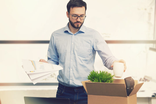 job loss - fired man putting his belongings in cardboard box
