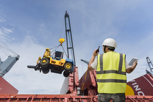 forman control loading the cargo by walkie talkie raio on the heavy crane services in background