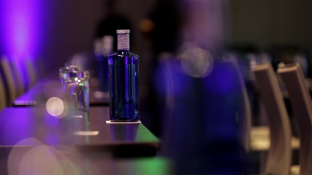 Bottles with water and transparent glasses on tables in meeting or conference hall. Getting rea
