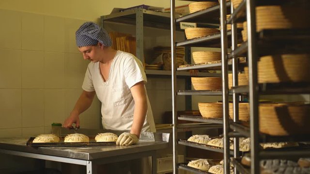 a Baker makes manual incisions on the dough for the bread. The Manufacture Of Bread.Bakery