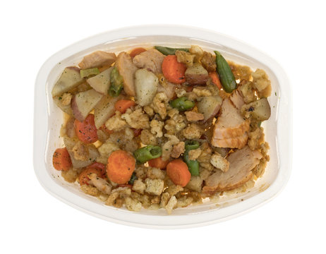Top view of a TV dinner of turkey breast with stuffing and vegetables isolated on a white background.