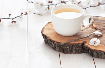 Weiße Tasse heißen Tee mit Frühlingsblumen auf hellem Holzhintergrund