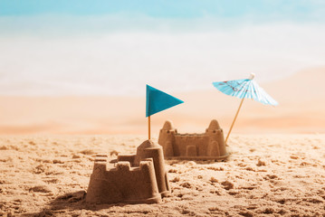 Fototapeta na wymiar Sandcastles with flag and umbrella on the beach.
