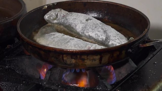 Dredged fish is frying on a pan slow motion