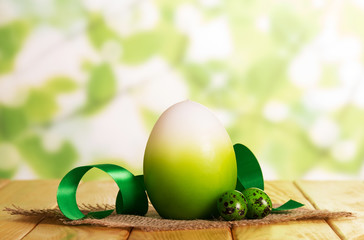 Various Easter eggs, feed and cloth on abstract green.