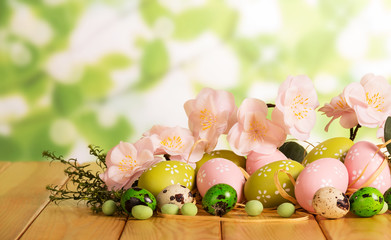 Various Easter eggs, candy, grass, flowers on abstract green.